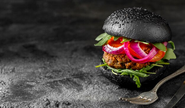 Front view veggie burger with black buns on cutting board with copy-space