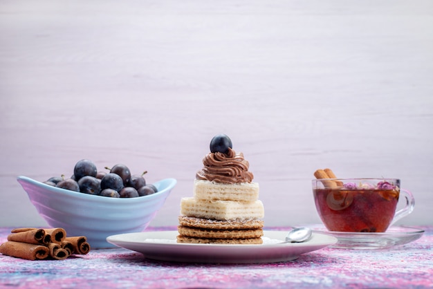 Front view waffle cakes with grapes cinnamon and tea on grey