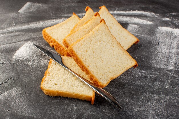 Front view white bread loafs sliced and tasty isolated with knife on grey