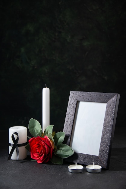 Front view white candle with picture frame and flower on the dark surface