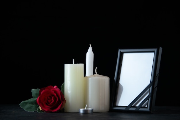 Free photo front view of white candles with red rose as memory on dark wall