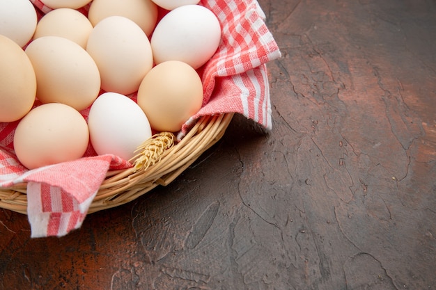 Front view white chicken eggs inside basket with towel on the dark surface