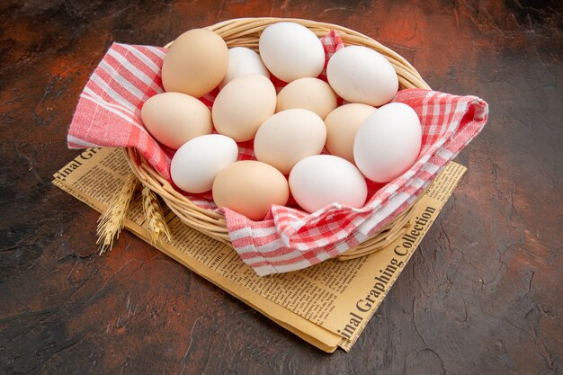 Front view white chicken eggs inside basket with towel on the dark surface