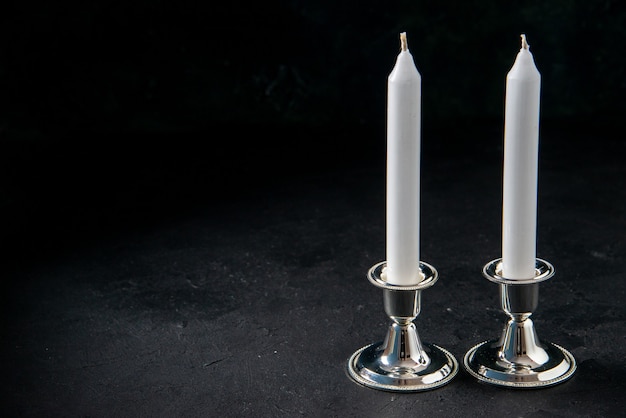 Front view of white long candles on dark floor war evil death funeral light