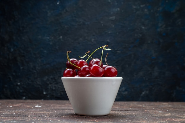 Front view white plate with sour red fresh cherries on brown wooden desk