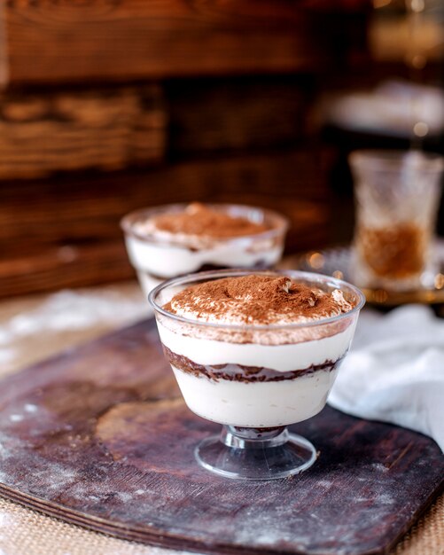 Front view white yummy dessert inside little glasses on the brown desk