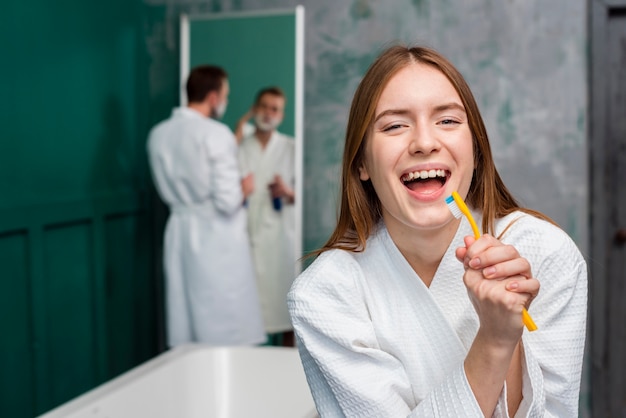 Free photo front view of woman in bathrobe singing in toothbrush