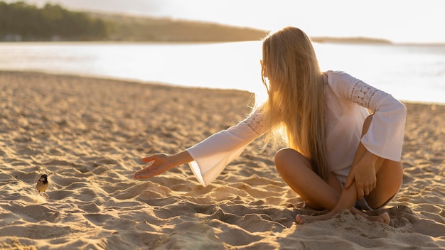 Front view of woman on the beach with bird