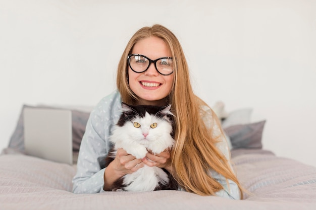 Free photo front view of woman in bed wearing pajamas with cat and laptop