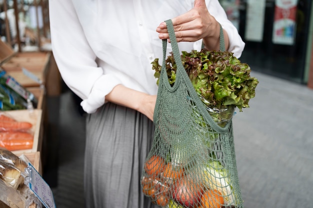 Free Photo front view woman carrying groceries in tote bag