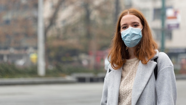 Front view of woman in the city wearing medical mask with copy space