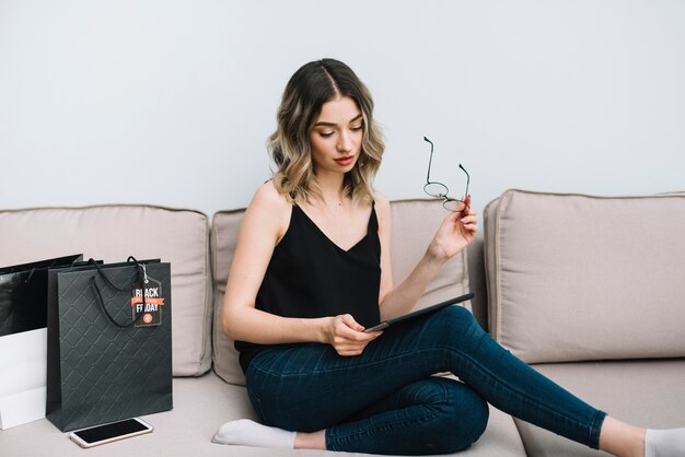 Front view woman on couch checking online black friday site