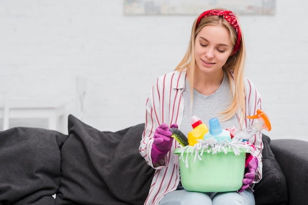 Free photo front view woman on couch with cleaning products