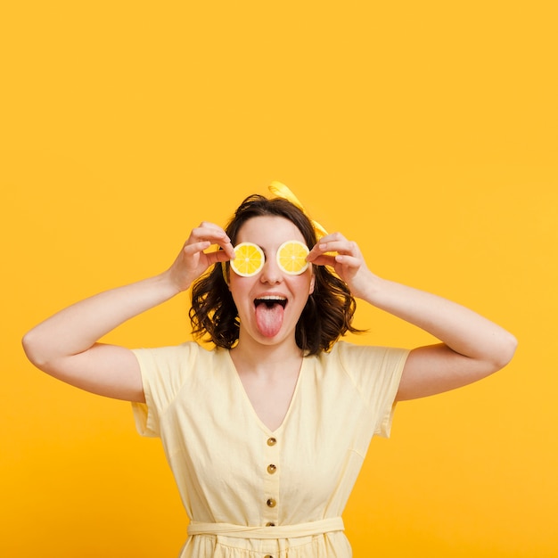 Free photo front view woman covering eyes with lemon slices