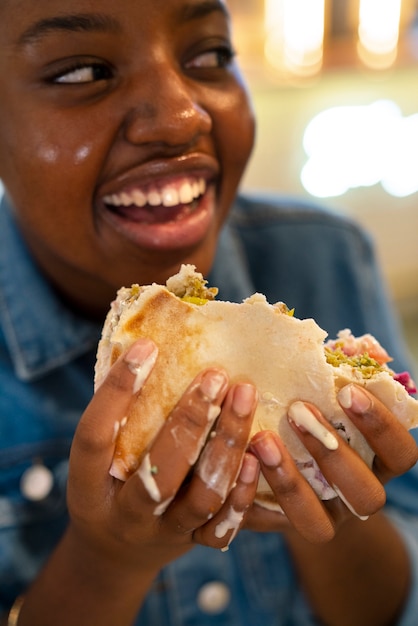 Front view woman eating burger in a funny way