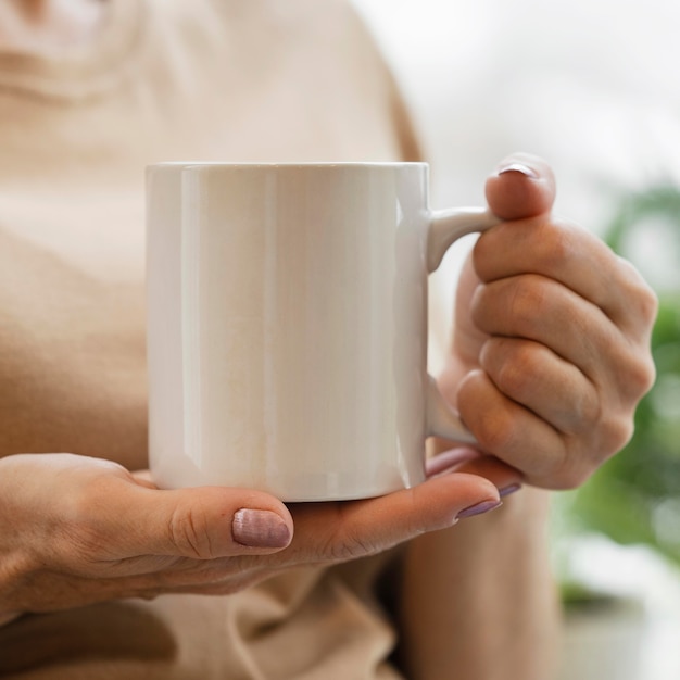 Front view of woman enjoying a drink in mug indoors