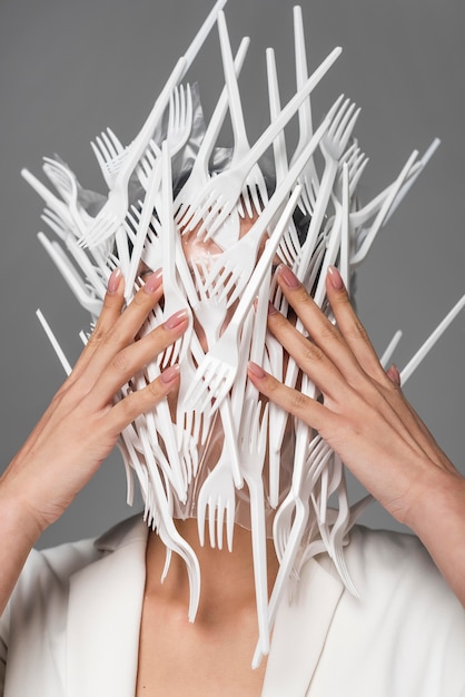 Free photo front view woman face being covered in white plastic forks