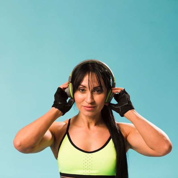 Front view of woman in gym outfit posing with headphones