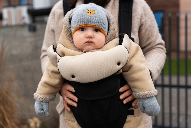 Front view woman holding baby in carrier