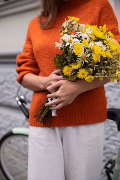 Front view of woman holding bouquet of flowers with bicycle