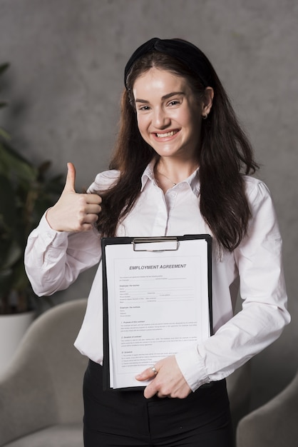 Free photo front view of woman holding contract and giving thumbs up