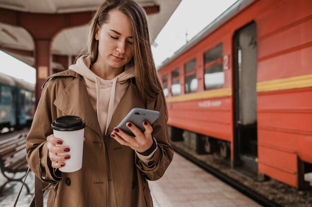 Front view woman holding a cup of coffee at the train station