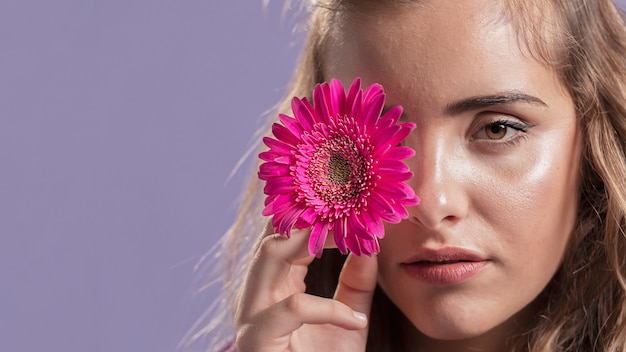 Front view of woman holding a flower near her face with copy space