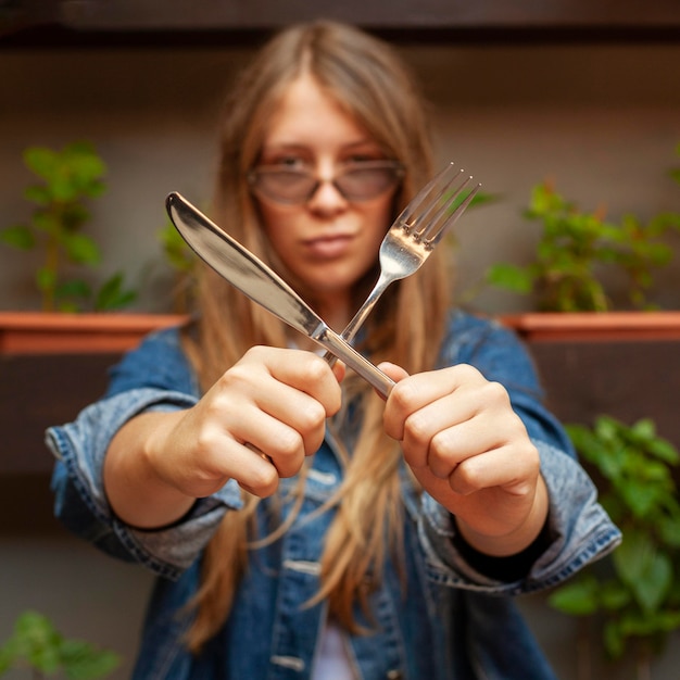 Free Photo front view of woman holding knife and fork in an x