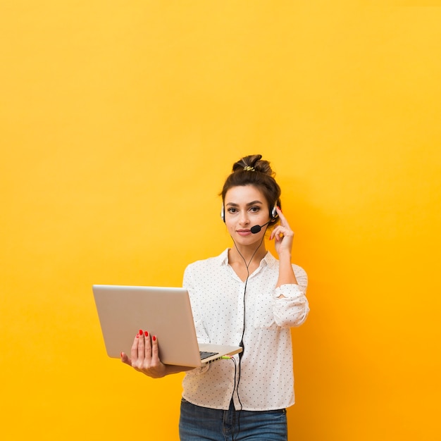 Front view of woman holding laptop ready to take calls on headset