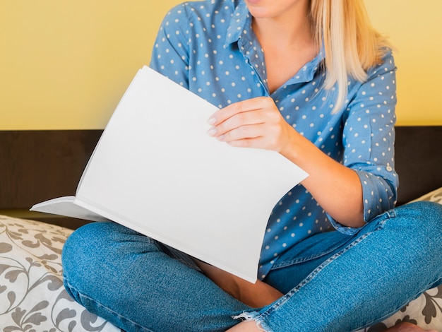 Free photo front view woman holding a mock-up magazine