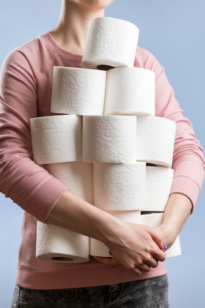 Front view of woman holding multiple toilet paper rolls