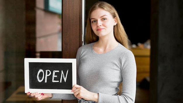 Front view of woman holding open sign for coffee shop