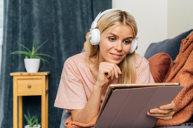 Free photo front view of woman at home on couch using tablet with headphones