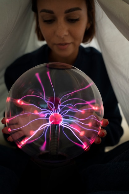 Free Photo front view woman interacting with a plasma ball