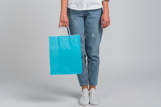 Front view of woman in jeans holding shopping bag