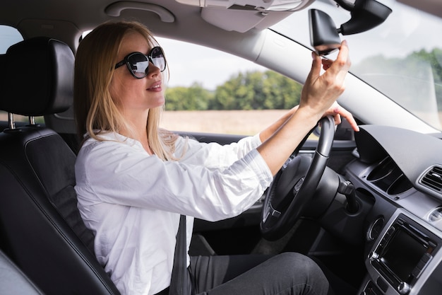 Free photo front view of a woman looking at rearview mirror