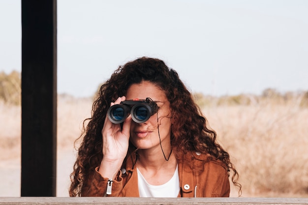 Free Photo front view woman looking through binoculars