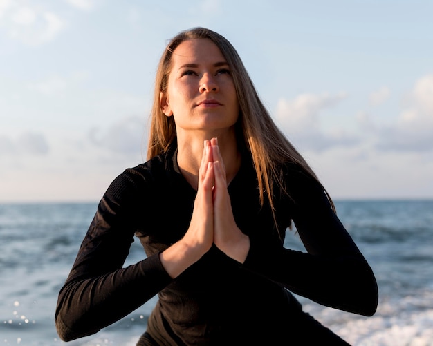 Front view woman meditating at the beach