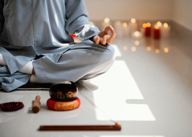 Free photo front view of woman meditating with incense and candles