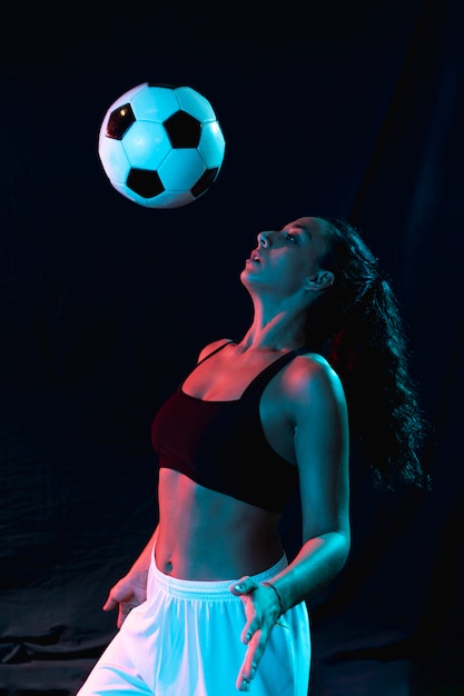 Front view woman playing with soccer ball