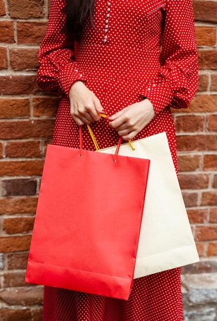 Front view of woman posing outside while holding multiple shopping bags