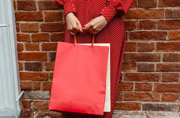 Front view of woman posing outside with multiple shopping bags