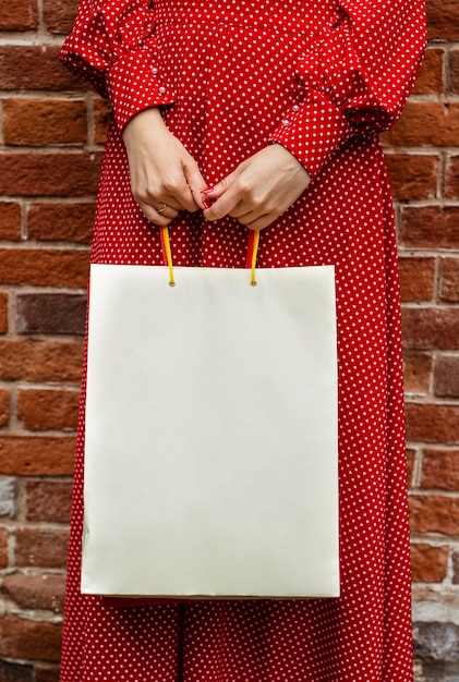 Front view of woman posing outside with shopping bag