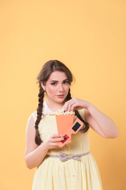 Front view of woman posing while holding popcorn and glasses