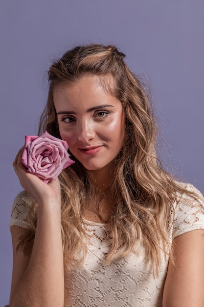 Free photo front view of woman posing while smiling and holding a rose