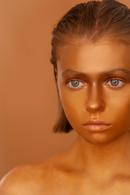 Front view woman posing with gold body painting