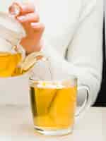 Free photo front view woman pouring tea from crystal teapot