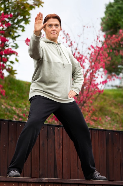 Free photo front view woman practicing tai chi outdoors