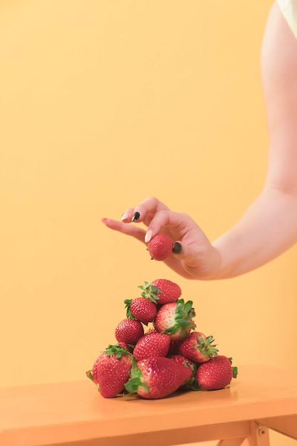 Front view of woman putting strawberry on top of pile