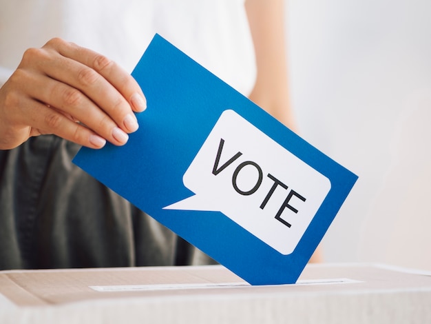 Front view woman putting a voting message in a box close-up